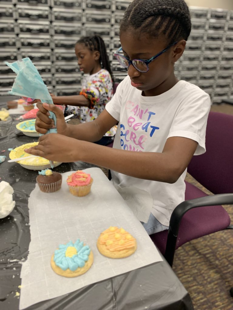 4-H student decorating cup cakes with frosting